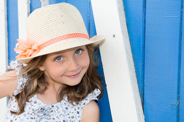 Close-up portrait of adorable smiling child girl wearing straw flowers hat