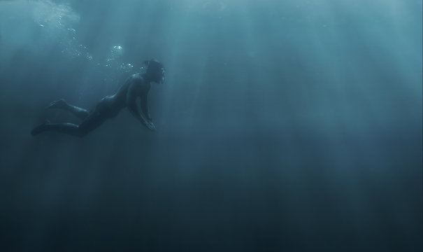 Male freediver snorkeling in deep sea.