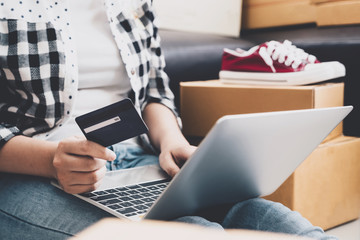 Young asian pretty girl using credit card and laptop computer for shopping online at home