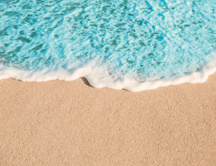Fototapeta na wymiar Soft Wave of Blue ocean in Summer. Empty Sandy Beach Textured Background with copy space for text..