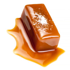 Homemade salted caramel piece isolated on white background with flowing sauce. Macro.