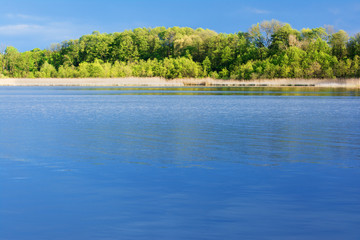 Fantastic beautiful blue lake view with green, spring forest background. Germany. 
