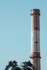 High red and white striped tube on background clear blue sky close-up. Thermal power plant with copy space.