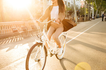 Cropped photo of young lady on bicycle on the street.