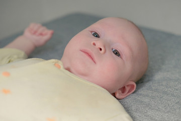 A small newborn boy lies on a bed