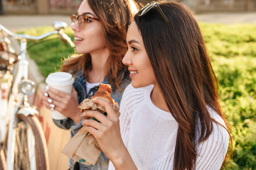 Two young beautiful women friends outdoors with bicycles