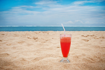 Tropical wallpaper glass of watermelon juice on a sandy beach.