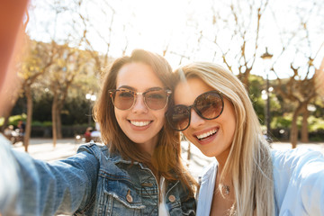 Two amazing cheerful women friends make selfie.
