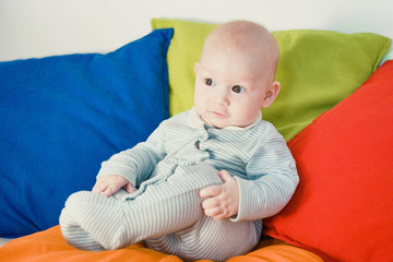 The kid sits on pillows