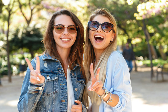 Amazing happy women friends outdoors showing peace gesture