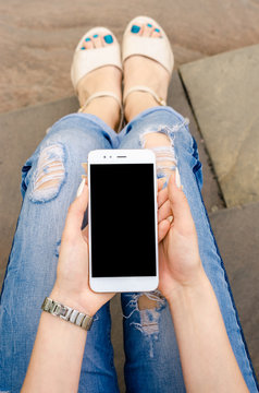 Close Up white Smartphone Mobile Cell holding in woman hands  Stylish Torn Jeans Long Nails Denim Black Oled Display Stone Background