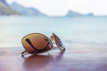 Fototapeta na wymiar Beach vacation. Sunglasses on a wooden table on a background, beach, ocean, hot summer day. Time for rest, happy way of life.