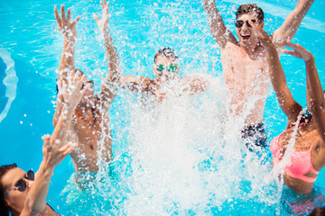 Cropped close up shot of youth going crazy in the pool, splitting water and go insane, huge splashes of blue clear water, guys jump and dabble.ladies, they scream and laugh