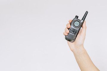 Holds a walkie-talkie in his hand on a gray background. Portable radio. Іsolated white background