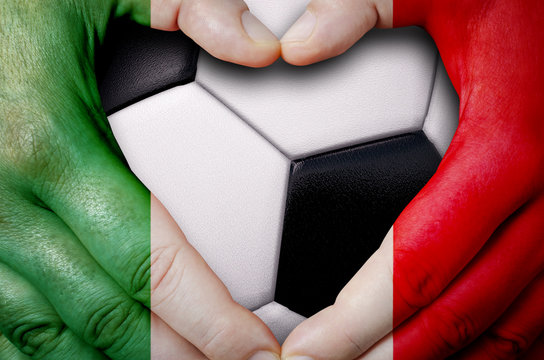 Hands painted with a Mexico flag forming a heart over soccer ball background