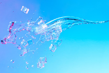 Water with ice cubes in vibrant bold gradient purple and blue holographic color lights. Concept...