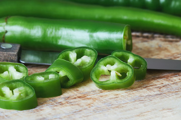 Fresh raw sliced green chili pepper on cutting board