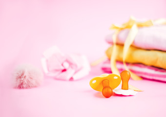 newborn stuff, clothes and pacifier for baby girl on pink background