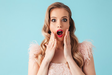 Surprised blonde woman in dress touching her cheeks