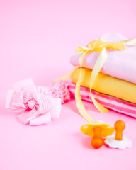 newborn stuff, clothes and pacifier for baby girl on pink background
