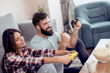 Joyful couple playing video games at home