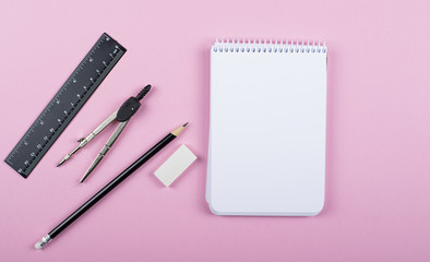 Notebook next to pencil, compass, ruler and eraser on pink background. Concept Back to school.