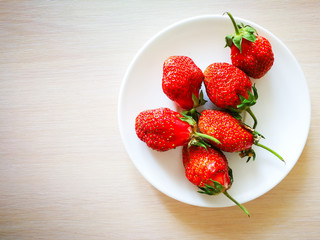 Спелая красная клубника на белой тарелке.