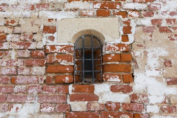 Window with a lattice in a brick wall of the monastery