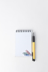Notepad, pen and paper clip on white background .photo with copy space