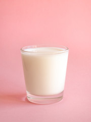 A glass of fresh milk on a pink background.