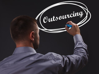 The concept of business, technology, the Internet and the network. Young businessman showing inscription: Outsourcing
