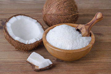 coconut flakes in a bowl on brown wooden background