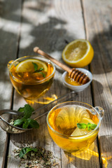 Summer tea - tea cups on rustic wood background with leaves shades - garden