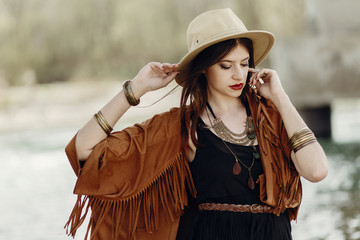 stylish hipster woman posing in hat with windy hair, in fringe poncho and accessory. boho traveler...