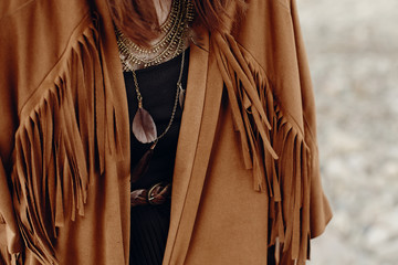 stylish hipster boho traveler woman look. gypsy girl in fringe jacket with feather bronze...