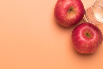 red apple and glass of water isolated on orange background,  healthy food and fitness concept