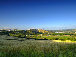 View of Arcos de la Frontera at sunset across a field of wheat from near the A-389, Andalucia, Spain