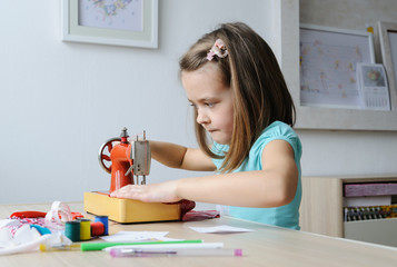 The girl is sewing on a sewing machine.