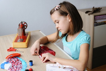 The girl is sewing on a sewing machine.