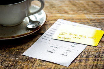 restaurant bill, card and coffee on wooden table background