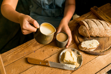 Fototapeta na wymiar Woman has breakfast adds milk to coffee