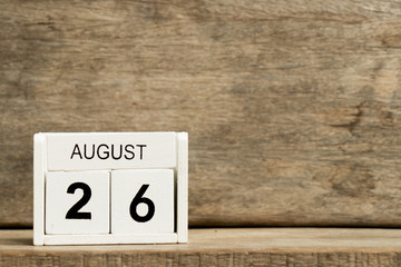 White block calendar present date 26 and month August on wood background
