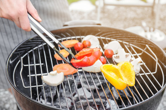 Man cooking juicy vegetables on barbecue grill