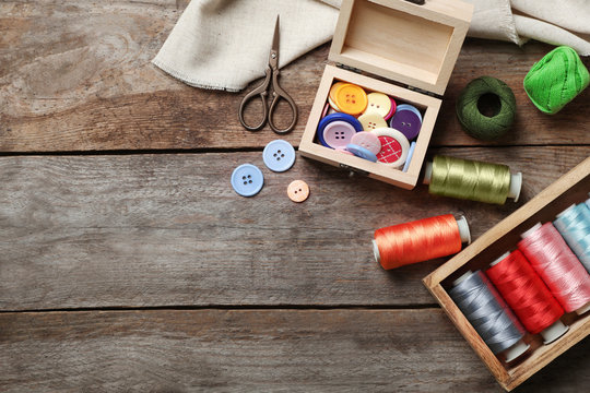 Composition with threads and sewing accessories on wooden background, top view