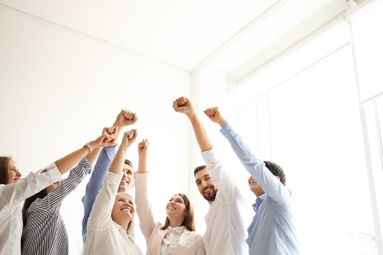 People raising fists together indoors. Unity concept