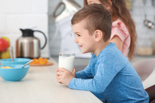 Cute little boy drinking milk in kitchen