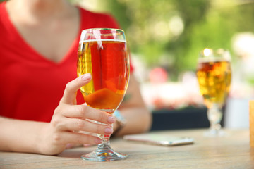 Young woman with glass of cold beer at table, closeup