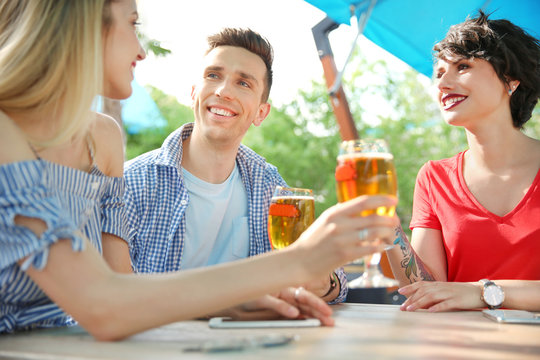 Young people with glasses of cold beer at table
