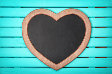 Empty heart shaped chalkboard on wooden background