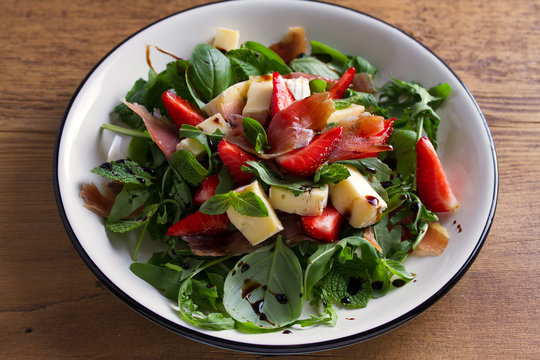 Strawberry, avocado, basil, mint, arugula salad with brie cheese and jamon or prosciutto. Healthy salad bowl
